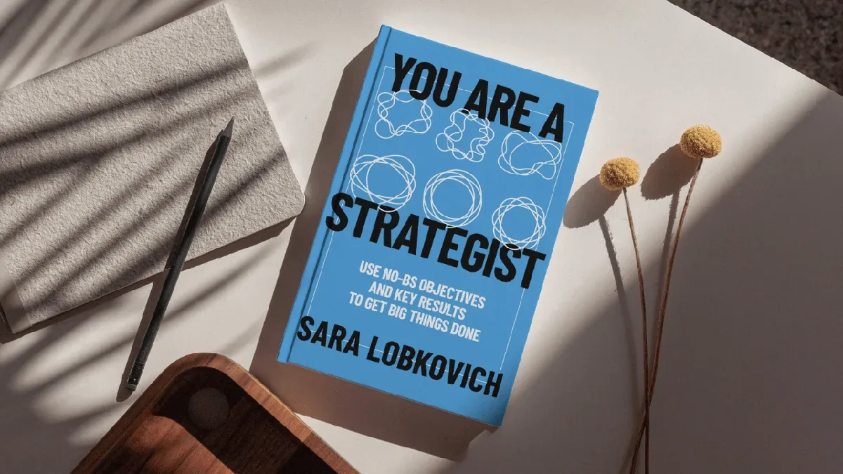 You Are a Strategist book on minimalist desk with pencil and dried flowers
