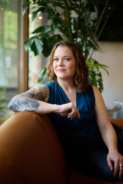 Sara Lobkovich relaxed on a leather couch, looking off-camera — authentic and thoughtful